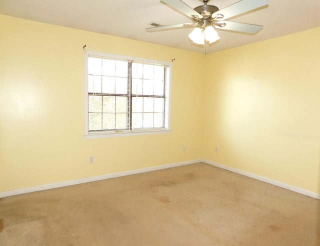 empty room with light colored carpet, a ceiling fan, and baseboards