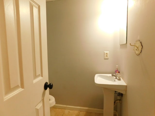 half bath featuring tile patterned floors, toilet, and baseboards