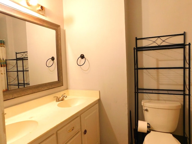 full bathroom with a sink, toilet, and double vanity