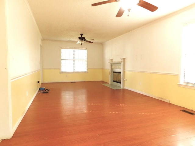 unfurnished living room featuring visible vents, a fireplace with flush hearth, wood finished floors, and ornamental molding