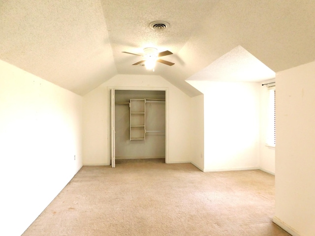 bonus room featuring visible vents, ceiling fan, carpet, vaulted ceiling, and a textured ceiling