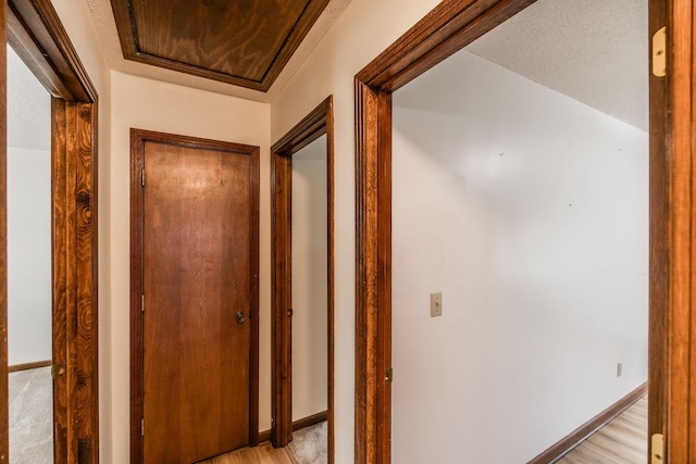 hallway featuring light wood finished floors and baseboards