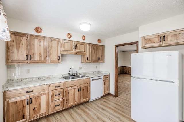 kitchen with a textured ceiling, white appliances, light wood-style flooring, and a sink