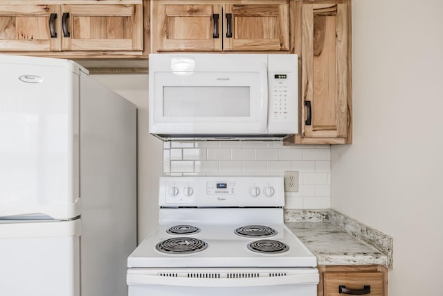 kitchen with tasteful backsplash, white appliances, and light stone counters