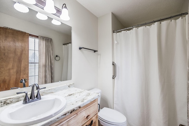 bathroom featuring vanity, a shower with shower curtain, toilet, and a textured ceiling