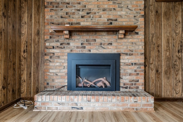 room details with wooden walls, a fireplace, baseboards, and wood finished floors