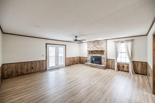 unfurnished living room featuring a wainscoted wall, plenty of natural light, a textured ceiling, and wood walls