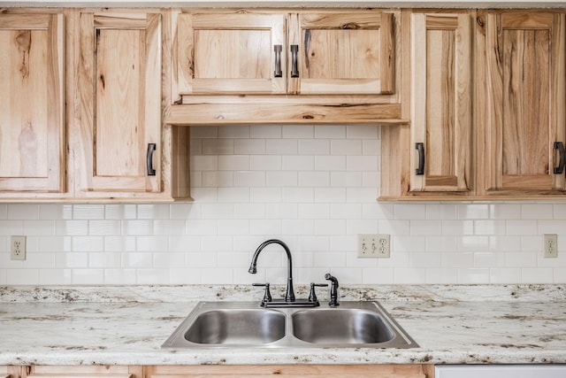 kitchen with light brown cabinetry, decorative backsplash, and a sink