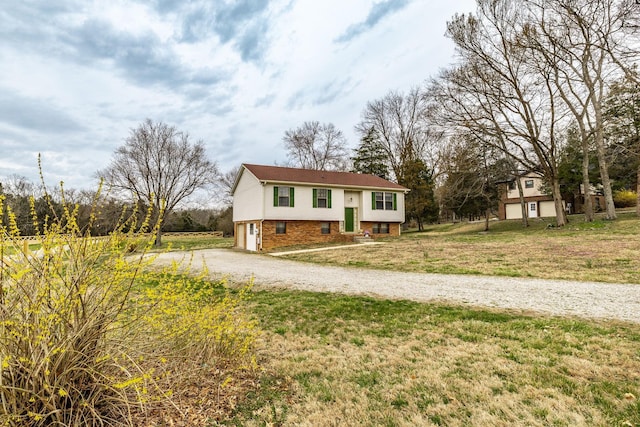 raised ranch with brick siding, driveway, an attached garage, and a front lawn