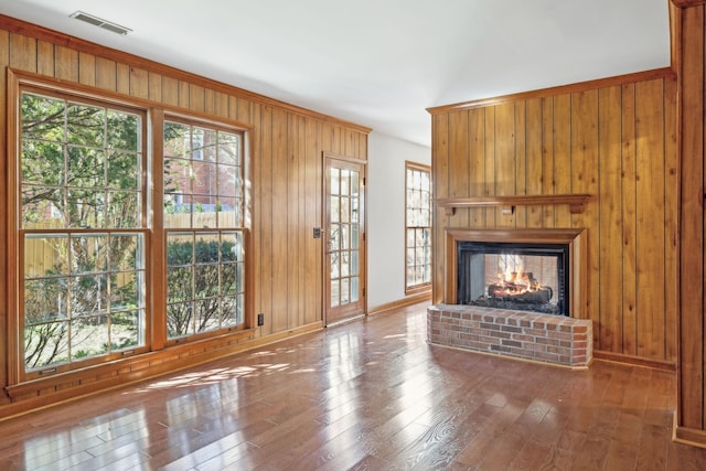 unfurnished living room featuring plenty of natural light, a fireplace, visible vents, and hardwood / wood-style flooring