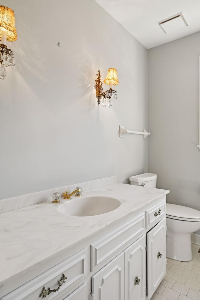 bathroom with vanity, toilet, and visible vents