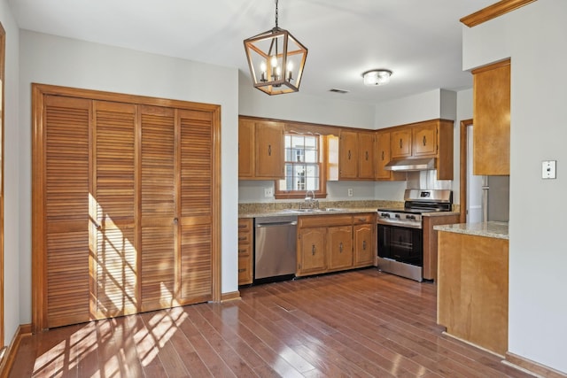 kitchen with dark wood-style floors, visible vents, a sink, under cabinet range hood, and appliances with stainless steel finishes