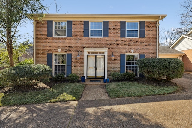 colonial-style house with brick siding and an attached garage