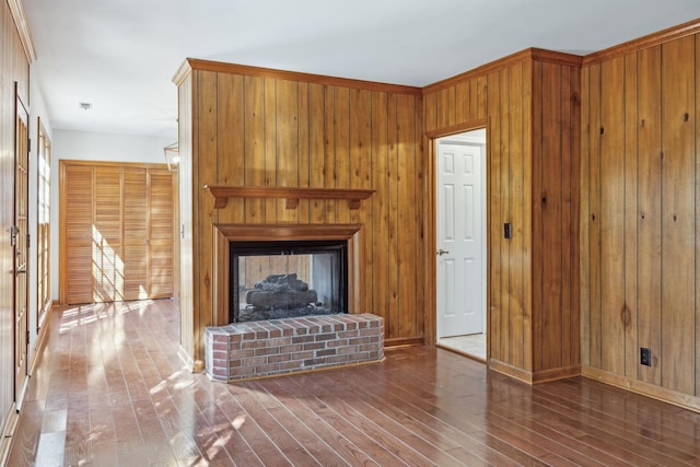 unfurnished living room with a fireplace, wood walls, and wood-type flooring