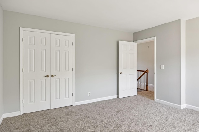 unfurnished bedroom featuring carpet, baseboards, and a closet