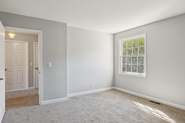 carpeted spare room featuring visible vents and baseboards