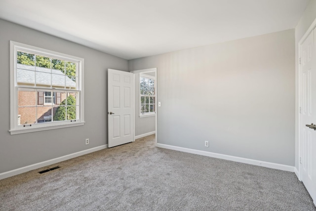 carpeted empty room featuring baseboards and visible vents