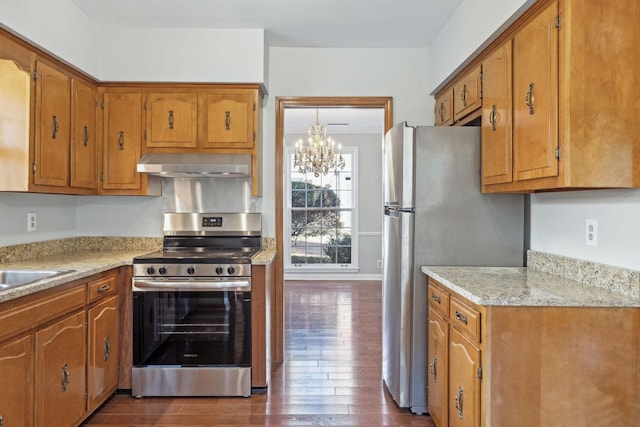 kitchen with extractor fan, dark wood finished floors, light countertops, brown cabinetry, and stainless steel appliances