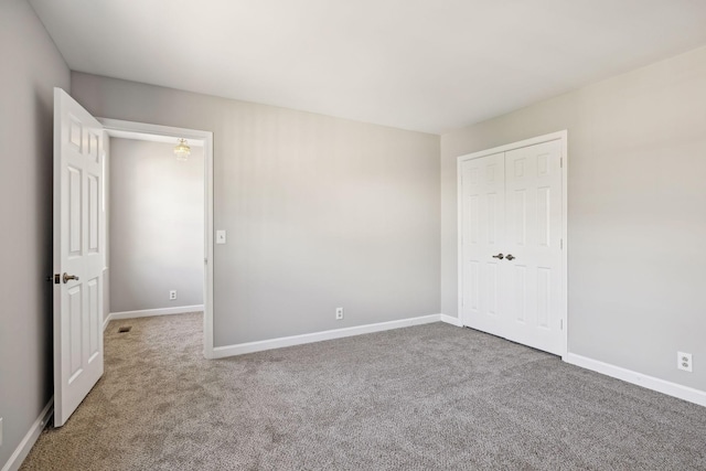 unfurnished bedroom with baseboards, carpet floors, and a closet