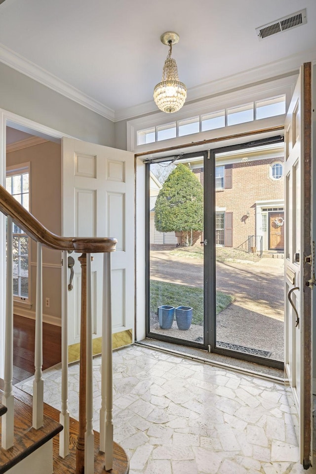 entrance foyer featuring visible vents, an inviting chandelier, crown molding, and stairway