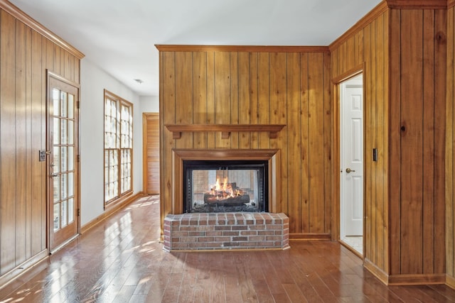 unfurnished living room with wooden walls, a fireplace, baseboards, and wood-type flooring