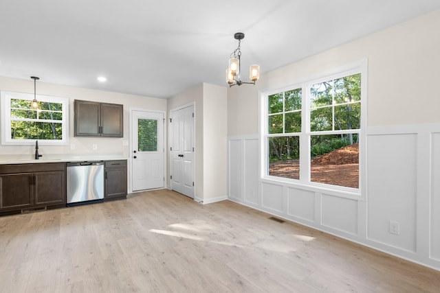 unfurnished dining area featuring visible vents, a sink, light wood-style floors, a decorative wall, and a chandelier