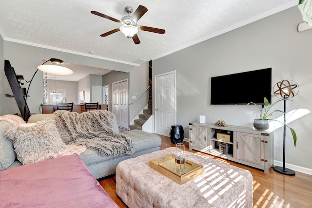 living room featuring stairs, crown molding, wood finished floors, and baseboards