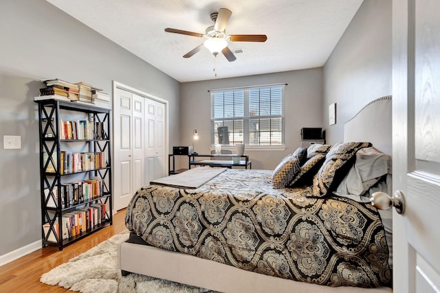 bedroom featuring visible vents, ceiling fan, baseboards, wood finished floors, and a closet