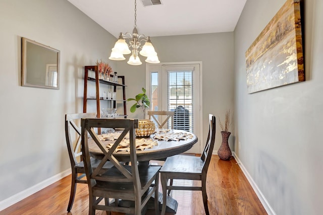 dining area with an inviting chandelier, baseboards, light wood-type flooring, and visible vents