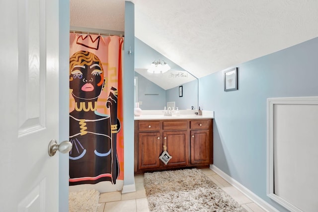 full bath with tile patterned floors, lofted ceiling, a textured ceiling, baseboards, and vanity