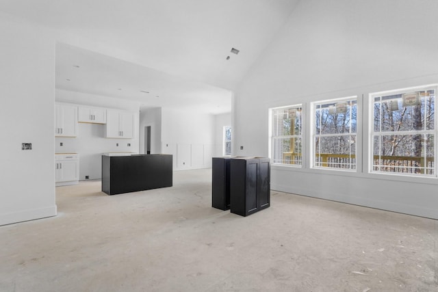 unfurnished living room featuring high vaulted ceiling and baseboards