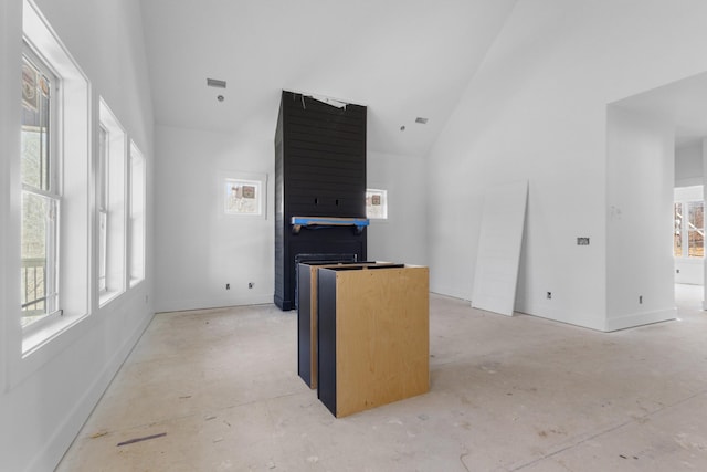 kitchen with baseboards, visible vents, high vaulted ceiling, unfinished concrete flooring, and a center island