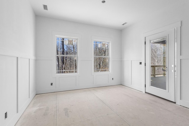 unfurnished room with a decorative wall, wainscoting, and visible vents