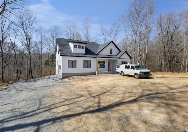 modern farmhouse style home featuring a view of trees and driveway