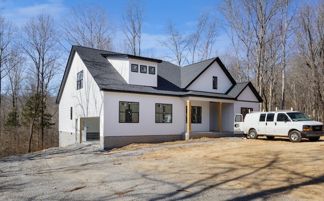 modern farmhouse featuring roof with shingles and a porch