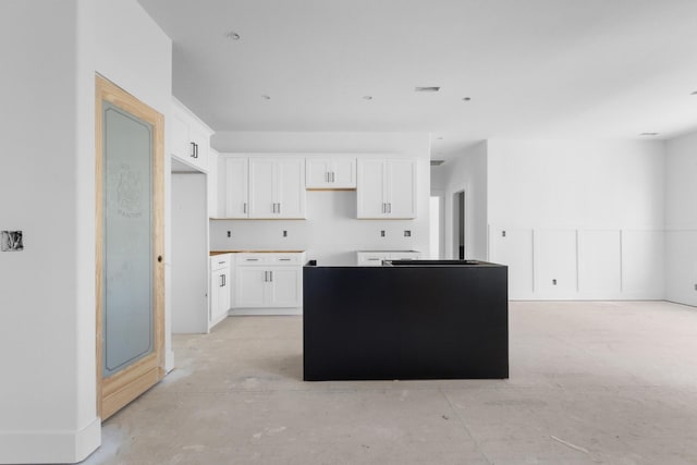 kitchen featuring white cabinets, concrete floors, and a center island