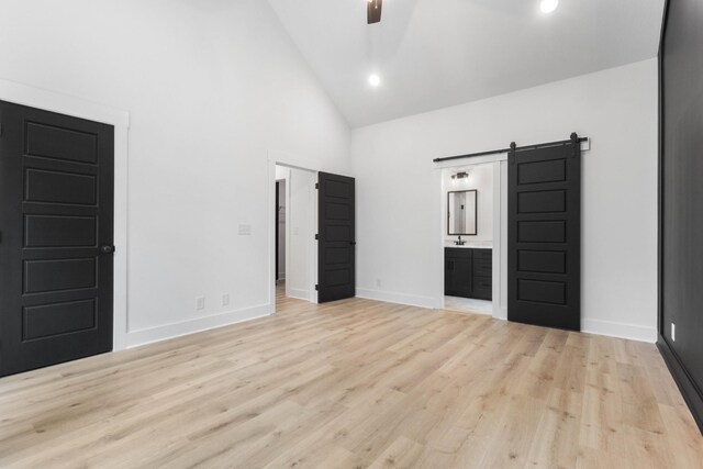 4410 Shiloh Canaan Rd, Palmyra, TN 37142 - unfurnished bedroom featuring a barn door, high vaulted ceiling, baseboards, wood finished floors, and ensuite bath