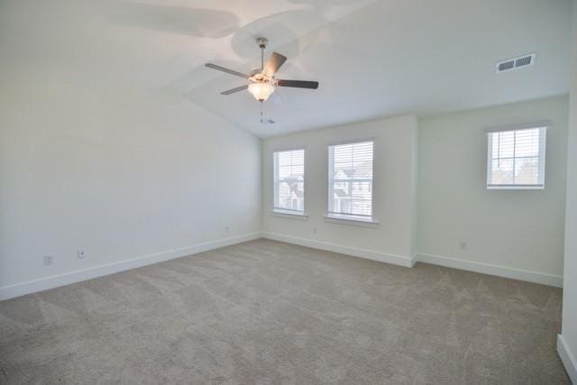 carpeted empty room featuring visible vents, ceiling fan, baseboards, and vaulted ceiling