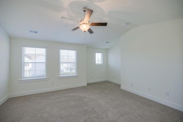 unfurnished room featuring visible vents, a ceiling fan, baseboards, light colored carpet, and vaulted ceiling