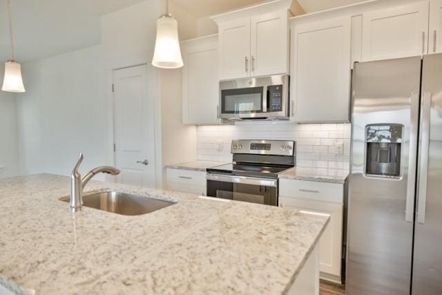 kitchen with light stone counters, decorative backsplash, appliances with stainless steel finishes, white cabinets, and a sink