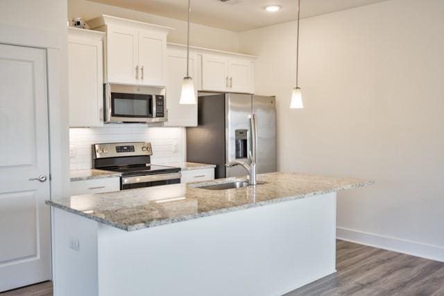 kitchen featuring backsplash, a center island with sink, white cabinets, stainless steel appliances, and a sink