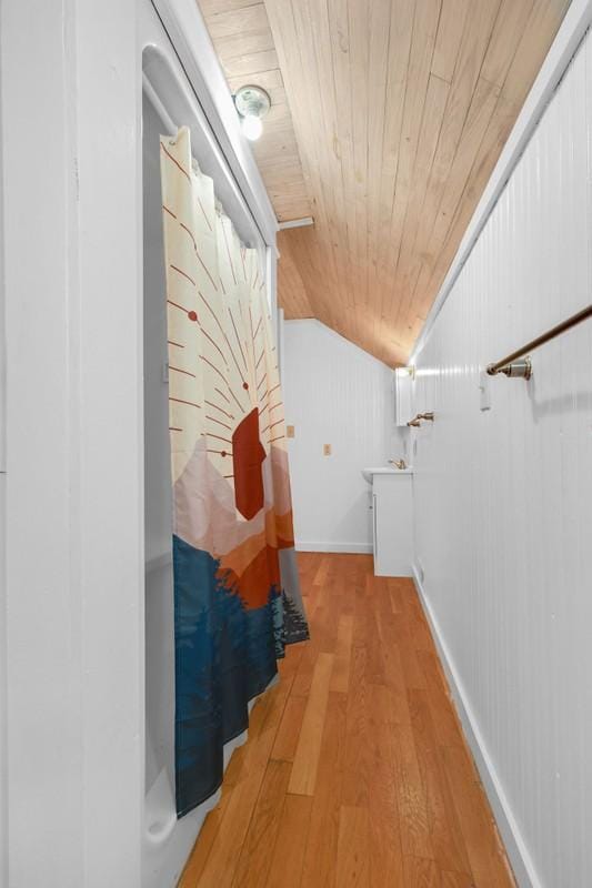 hall with light wood-style flooring, wooden ceiling, and vaulted ceiling