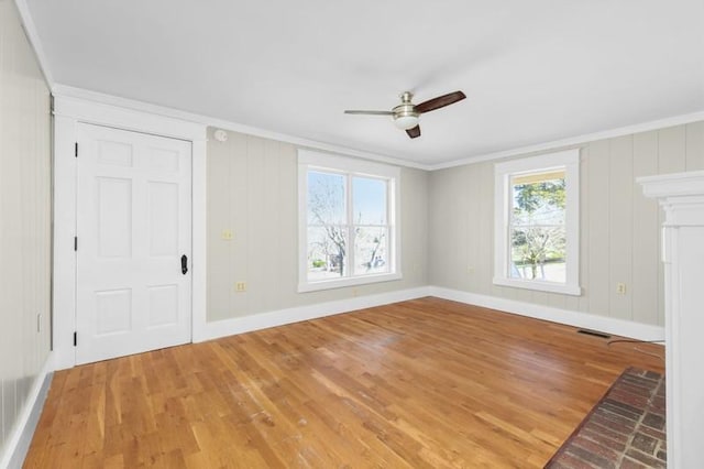 unfurnished living room with light wood-style flooring, baseboards, a ceiling fan, and ornamental molding