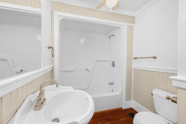 bathroom featuring toilet, ornamental molding, wainscoting, wood finished floors, and a sink