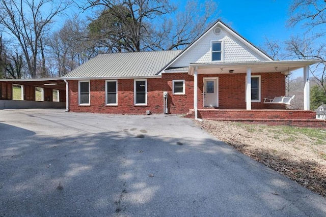 exterior space with brick siding, covered porch, an attached carport, and concrete driveway