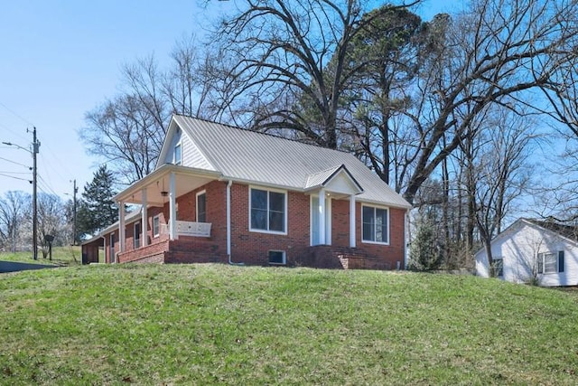 view of front facade featuring metal roof, brick siding, and a front lawn