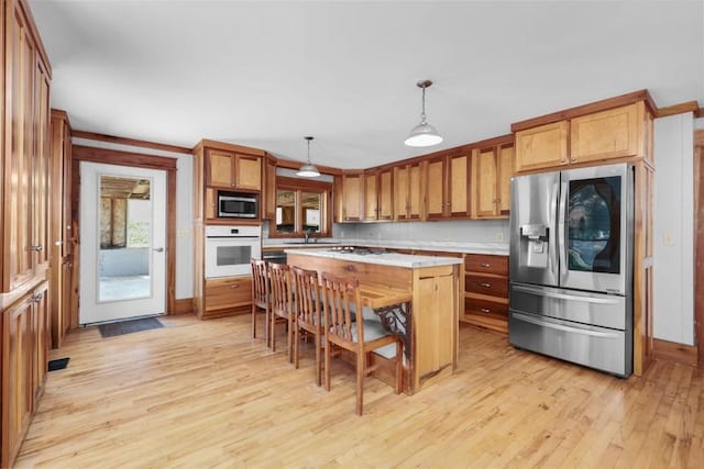kitchen with stainless steel appliances, light wood-style flooring, a center island, and light countertops