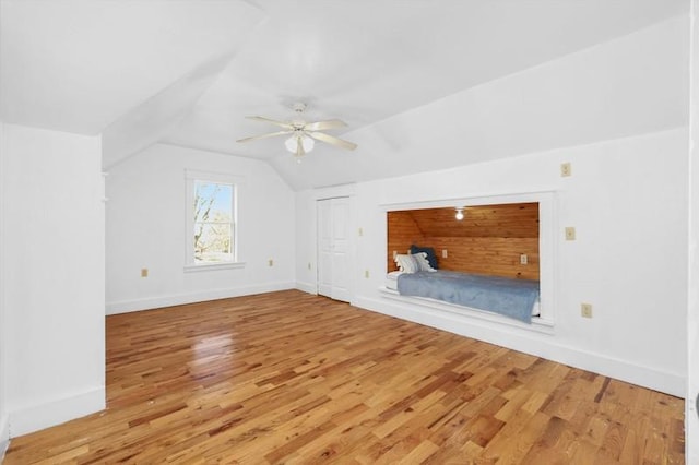 additional living space featuring baseboards, light wood-type flooring, ceiling fan, and vaulted ceiling