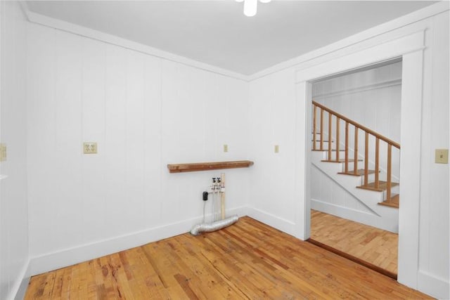 laundry area featuring crown molding, baseboards, and wood finished floors