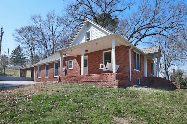view of front of property with driveway, covered porch, a front yard, an attached carport, and brick siding